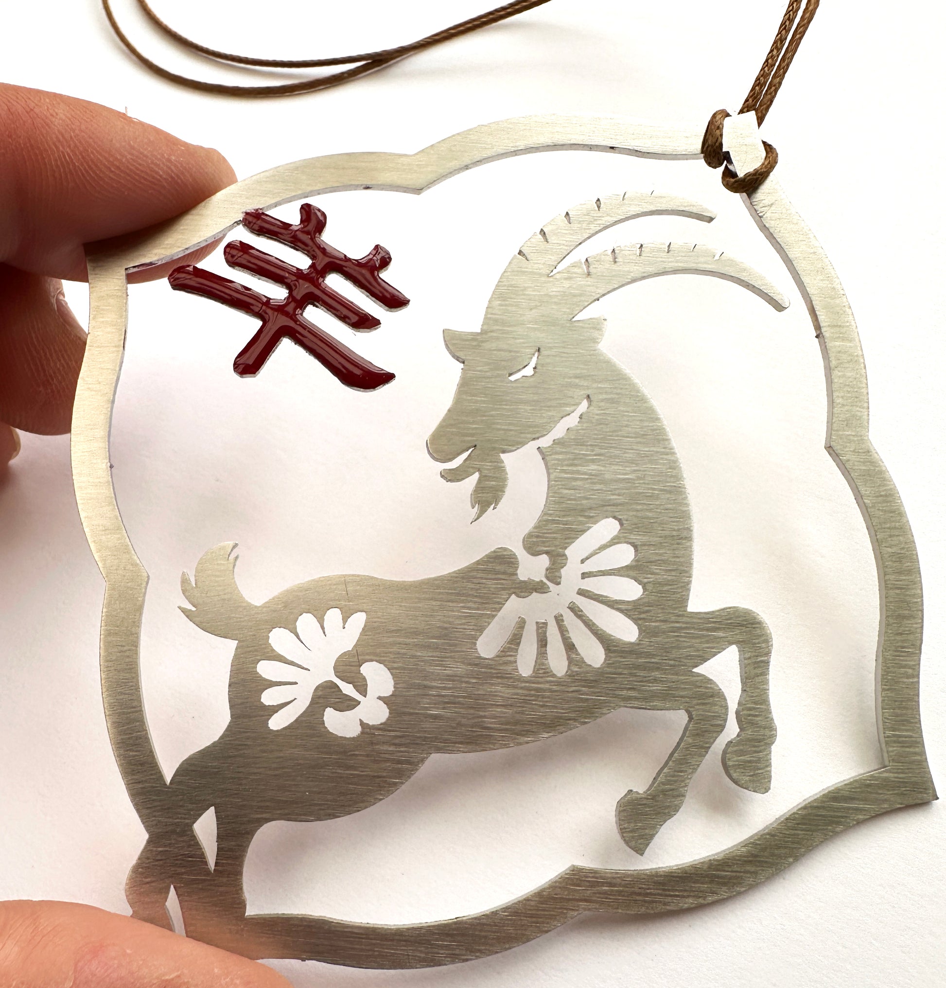 a person holding a metal ornament with a goat on it